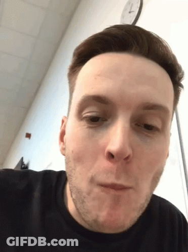 Man With Clock Saying 7:15 Behind Him GIF