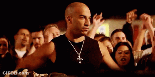 Man With Cross Necklace Standing Before Crowd GIF
