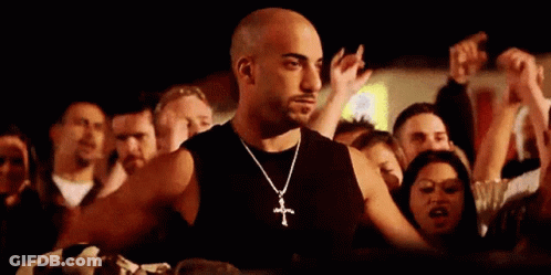 Man With Cross Necklace Standing In Front Of Crowd GIF