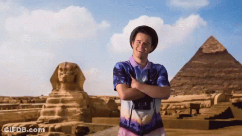 Man With Crossed Arms In Front Of Pyramid And Statue GIF