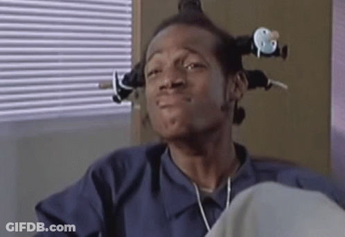 Man With Curlers Sitting By Blinds GIF