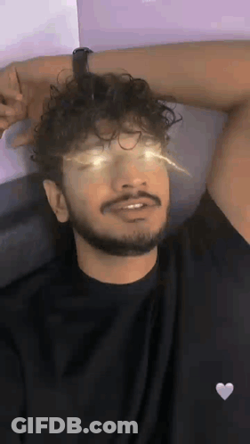 Man With Curly Hair And Beard Laying On Bed Eyes Closed Arm Outstretched GIF
