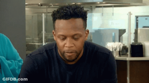 Man With Curly Hair And Beard Sitting In Kitchen Eyes Closed GIF