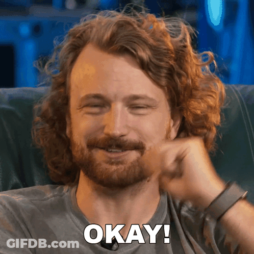 Man With Curly Hair And Beard Smiling Says Okay GIF