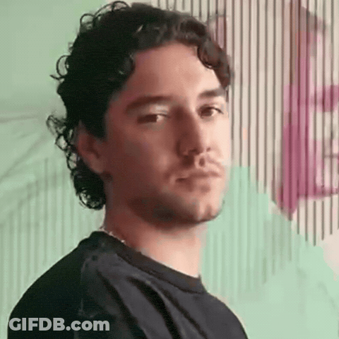 Man With Curly Hair And Beard Standing Before Striped Wall GIF