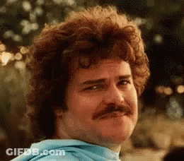 Man With Curly Hair And Mustache Looking At Camera GIF
