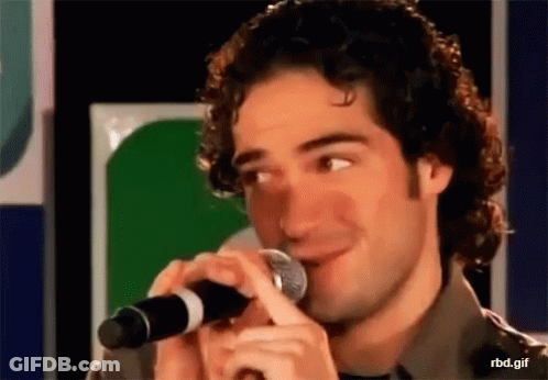 Man With Curly Hair Holding Microphone Smiling GIF