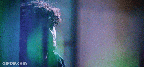 Man With Curly Hair In Front Of Blue Wall GIF
