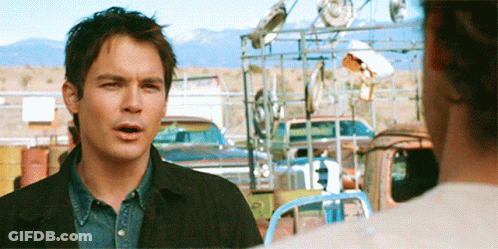 Man With Curly Hair In Front Of Blue Wall GIF