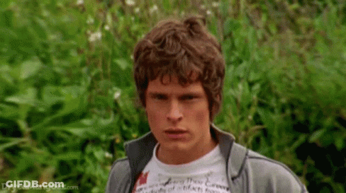 Man With Curly Hair In Gray Jacket And White T-Shirt GIF