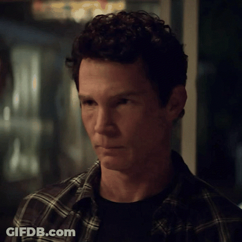 Man With Curly Hair In Plaid Shirt Looking At Camera GIF