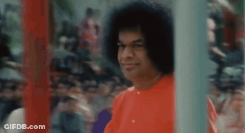 Man With Curly Hair In Red Shirt Standing Before Crowd GIF
