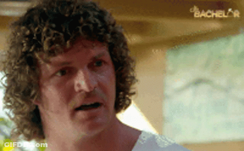 Man With Curly Hair In White Shirt Looking At Something GIF