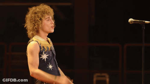 Man With Curly Hair Singing In Blue And Gold Outfit GIF