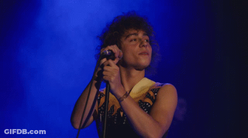 Man With Curly Hair Singing Into Microphone GIF