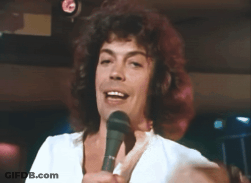 Man With Curly Hair Singing Into Microphone GIF