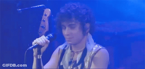 Man With Curly Hair Singing Into Microphone GIF