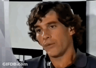 Man With Curly Hair Sitting In Front Of Checkered Wall Talking GIF