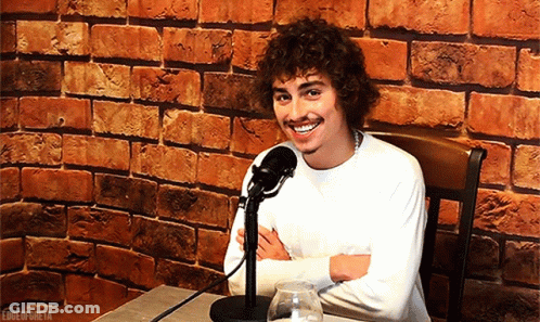 Man With Curly Hair Smiling At Microphone GIF