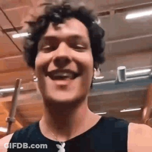 Man With Curly Hair Smiling In Gym Wearing Playboy Necklace GIF