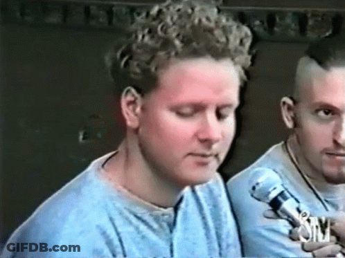 Man With Curly Hair Talking Into Microphone Another Man Looks On GIF