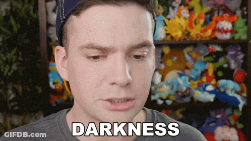 Man With Darkness Word In Front Of Stuffed Animal Shelf GIF
