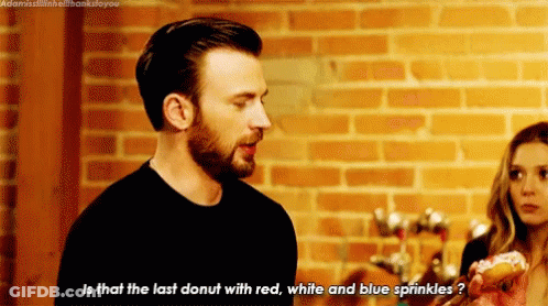 Man With Donut Talking To Woman In Front Of Brick Wall GIF