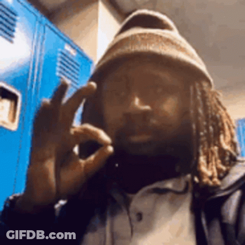 Man With Dreadlocks And Beanie Making Peace Sign At Blue Lockers GIF