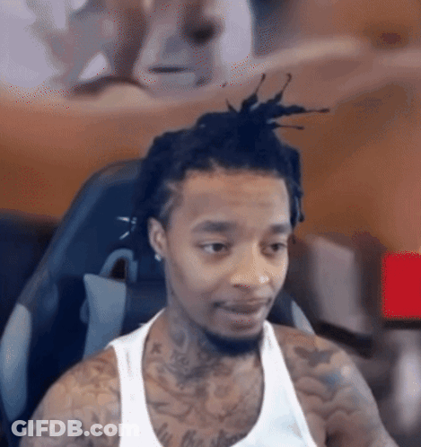 Man With Dreadlocks And Tattoos Looking At Camera GIF