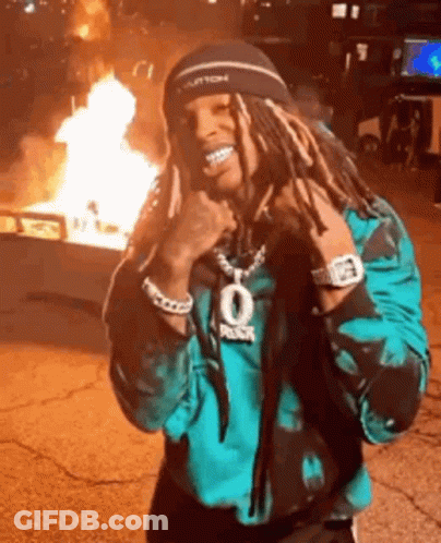 Man With Dreadlocks By Fire In Parking Lot GIF