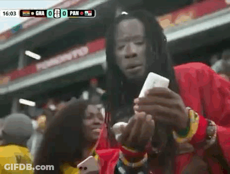 Man With Dreadlocks Holding Cell Phone At Soccer Game GIF