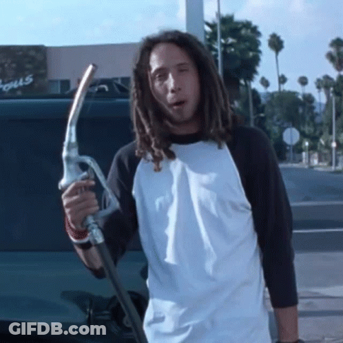 Man With Dreadlocks Holding Gas Pump In Front Of Focus Building GIF