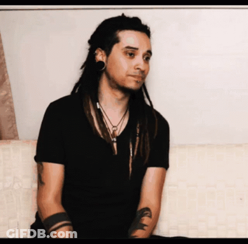 Man With Dreadlocks In Black Shirt And Arm Tattoo GIF
