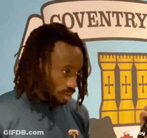 Man With Dreadlocks In Front Of Coventry Sign GIF