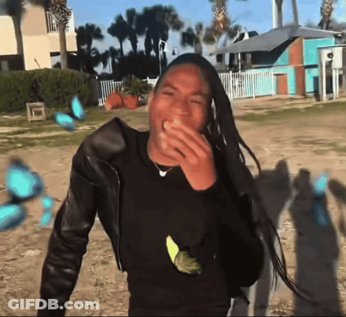 Man With Dreadlocks Laughing In Front Of Blue Building GIF
