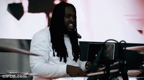 Man With Dreadlocks Sitting At Laptop With Coachella Sign GIF