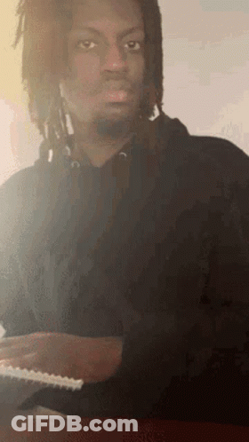 Man With Dreadlocks Sitting At Table With Notebook GIF