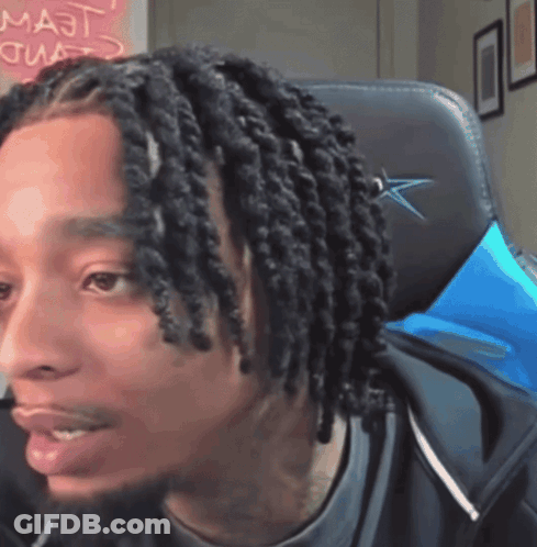 Man With Dreadlocks Sitting In Chair With Majt On Wall GIF