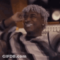 Man With Dreadlocks Sitting On Couch Hands Behind Head GIF