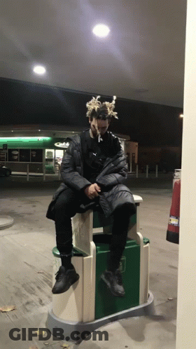 Man With Dreadlocks Sitting On Trash Can GIF