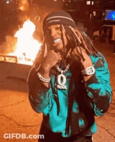 Man With Dreadlocks Smiling By Fire GIF