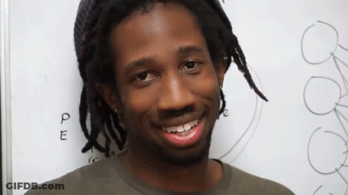 Man With Dreadlocks Smiling In Front Of PE Board GIF