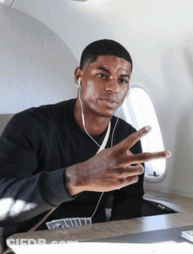 Man With Ear Buds Giving Peace Sign On Airplane GIF