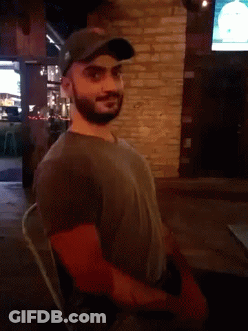 Man With Ear Piercing Looking At Camera In Dark Room GIF
