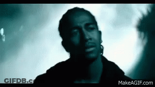 Man With Ear Piercing Looking At Camera In Dark Room GIF