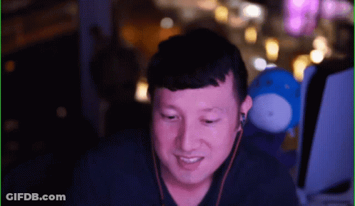 Man With Earbuds Smiling In Front Of Blue Stuffed Animal GIF