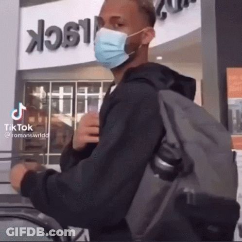 Man With Face Mask And Backpack In Front Of Building Saying Black GIF