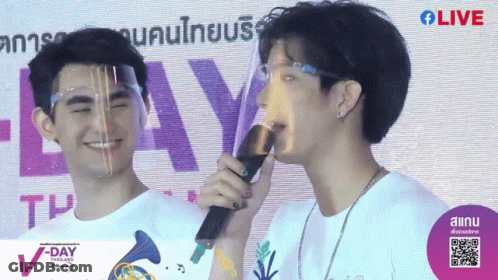 Man With Face Shield Holding Microphone In Front Of V-Day Thailand Sign GIF