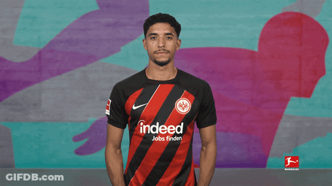 Man With Folded Hands In Front Of Bundesliga Mural GIF