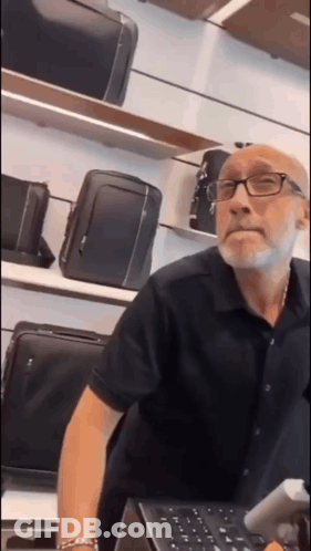 Man With Glasses And Beard At Luggage Counter GIF